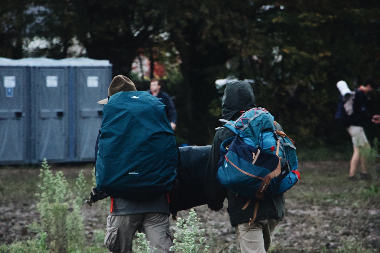 services-04 Two hikers with backpacks walking through a forest during the daytime, engaging in adventure and exploration.